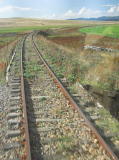 The rail cutting continues to the right, surrounded by farm land.