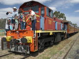 People pose for photographs on the front of diesel 7319 at Royalla station.